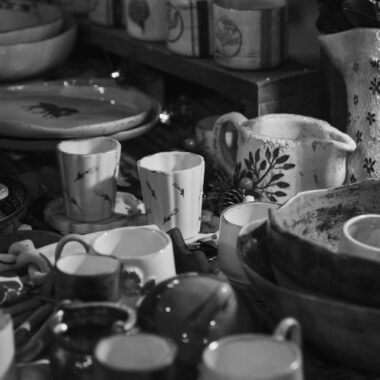 A collection of varied ceramic dishes and cups on display in monochrome.