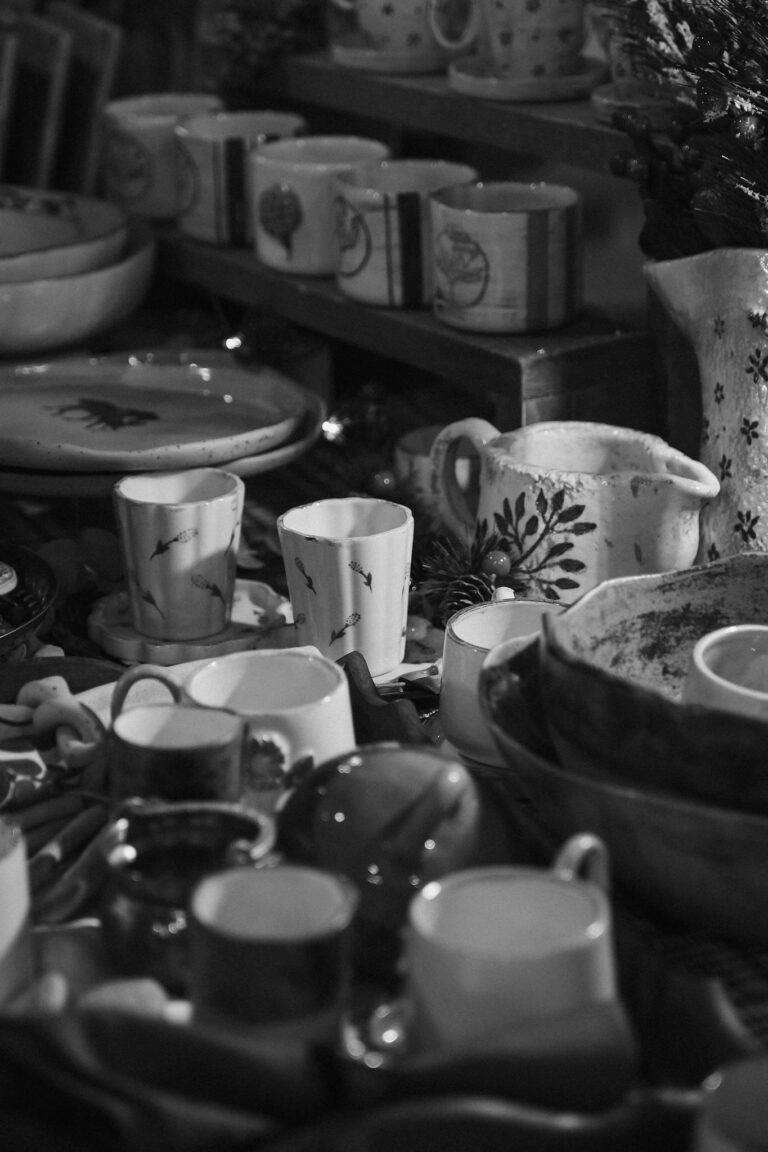 A collection of varied ceramic dishes and cups on display in monochrome.