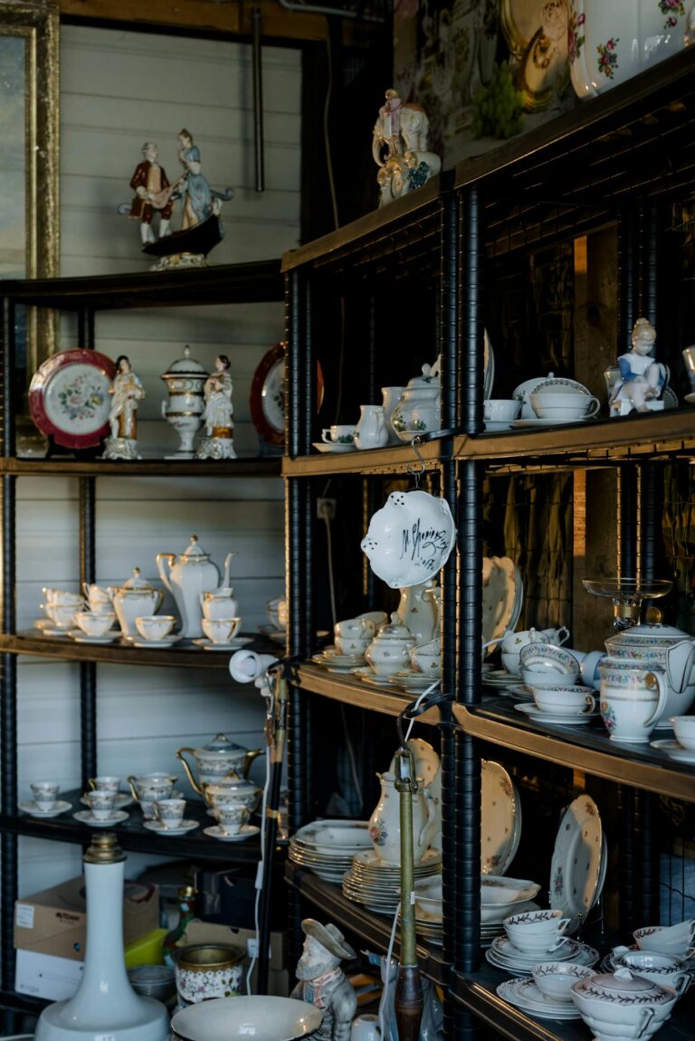 A collection of vintage porcelain and ceramic tableware on shelves, showcasing delicate craftsmanship.