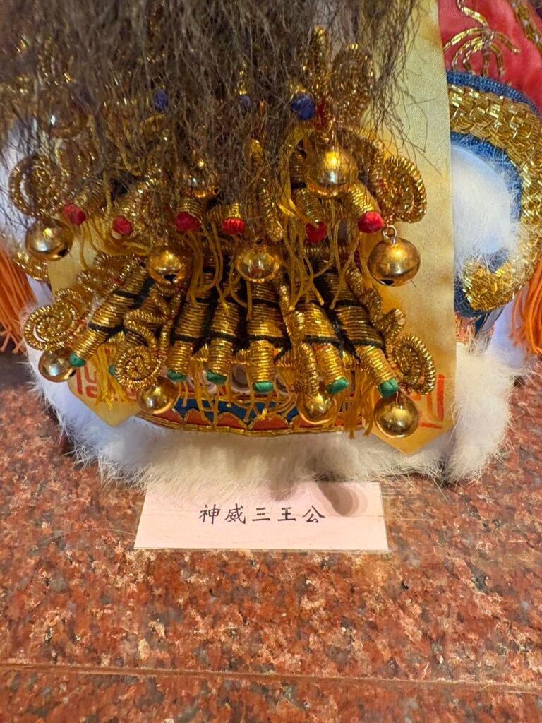 Close view of elaborate gold-thread ornament on a Gu Gong San Wang figure